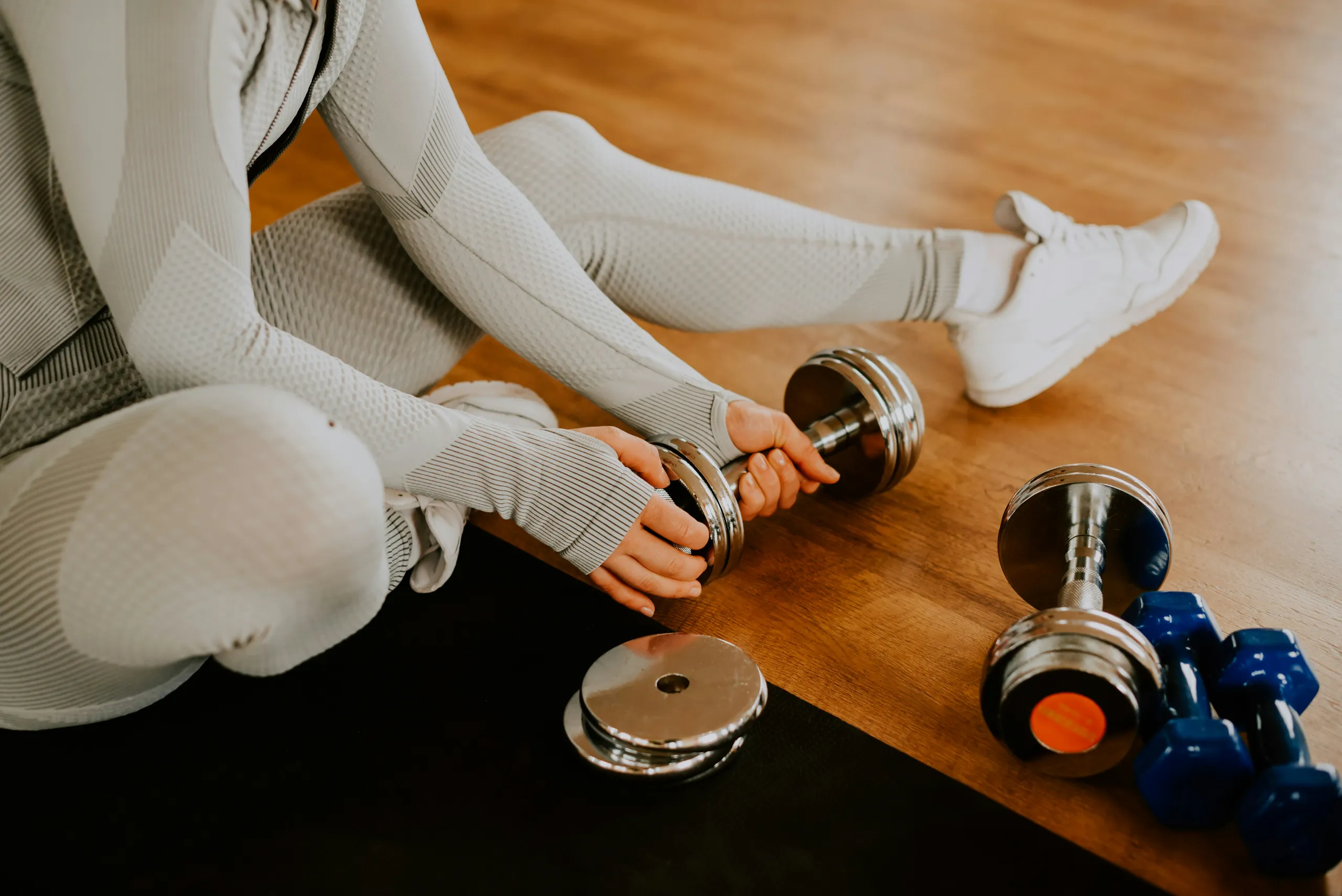 Mujer con mancuernas durante un entrenamiento de fuerza en el suelo del estudio