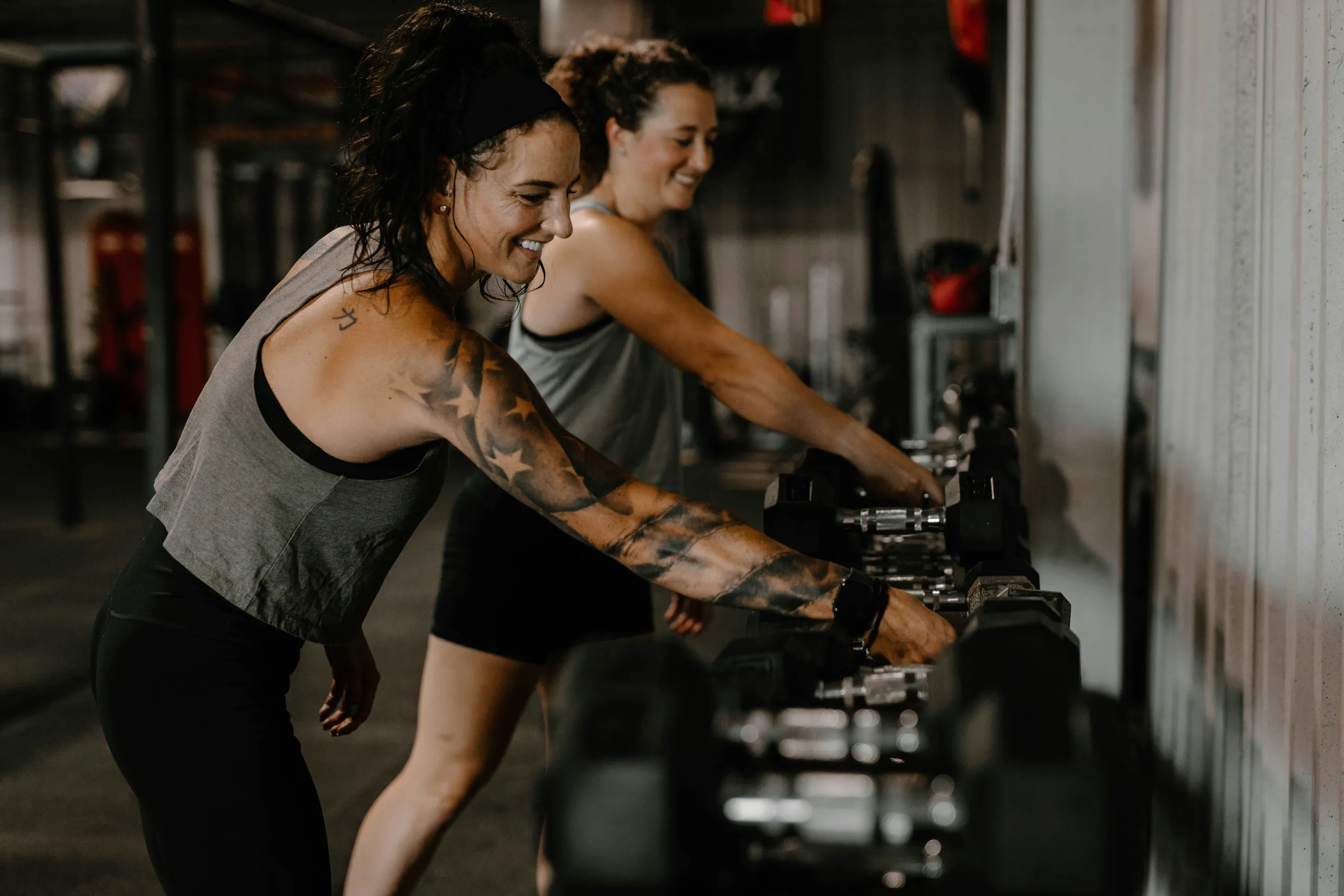 Dos mujeres sonrientes entrenan con mancuernas en un grupo reducido